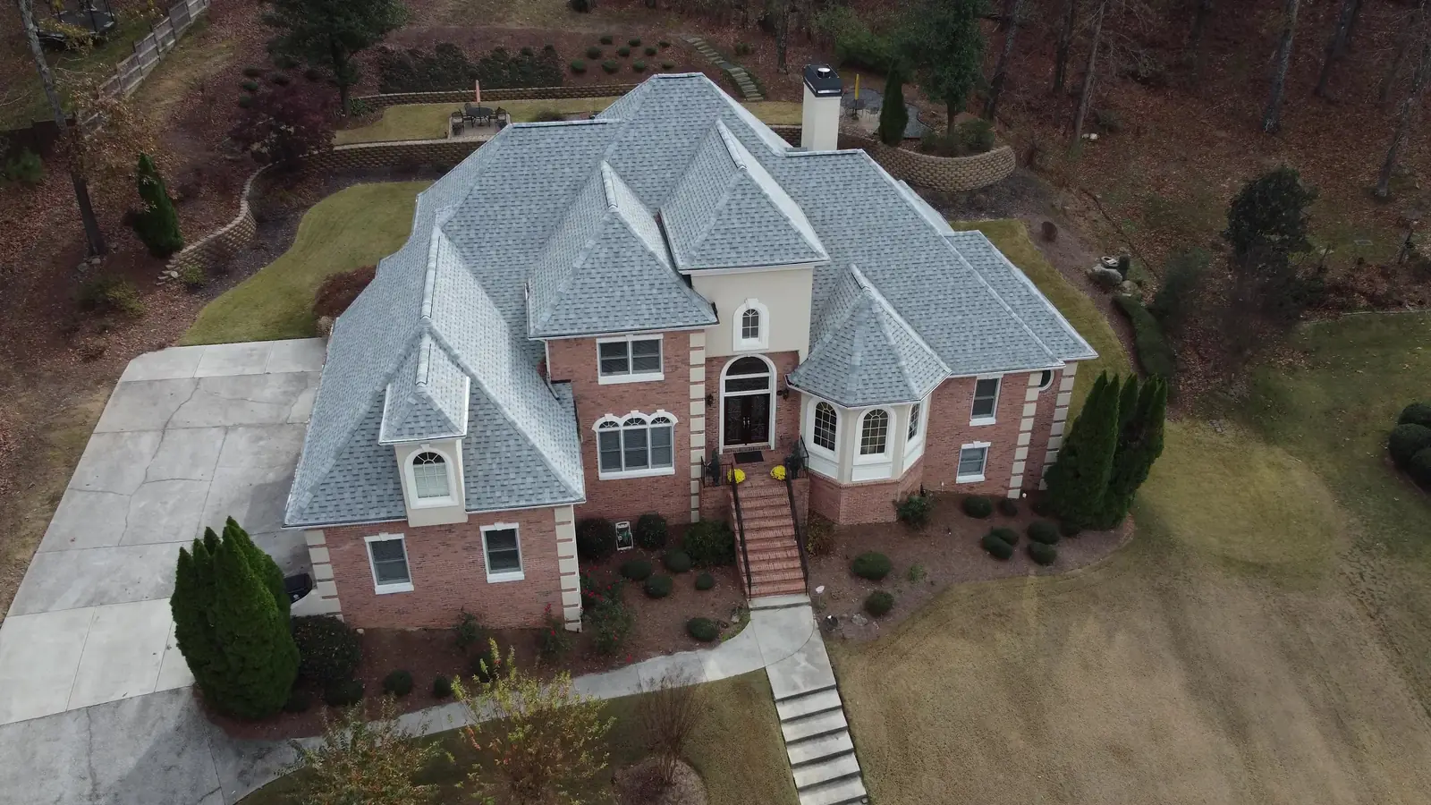 Aerial view of a light gray shingle roof on a large brick estate home